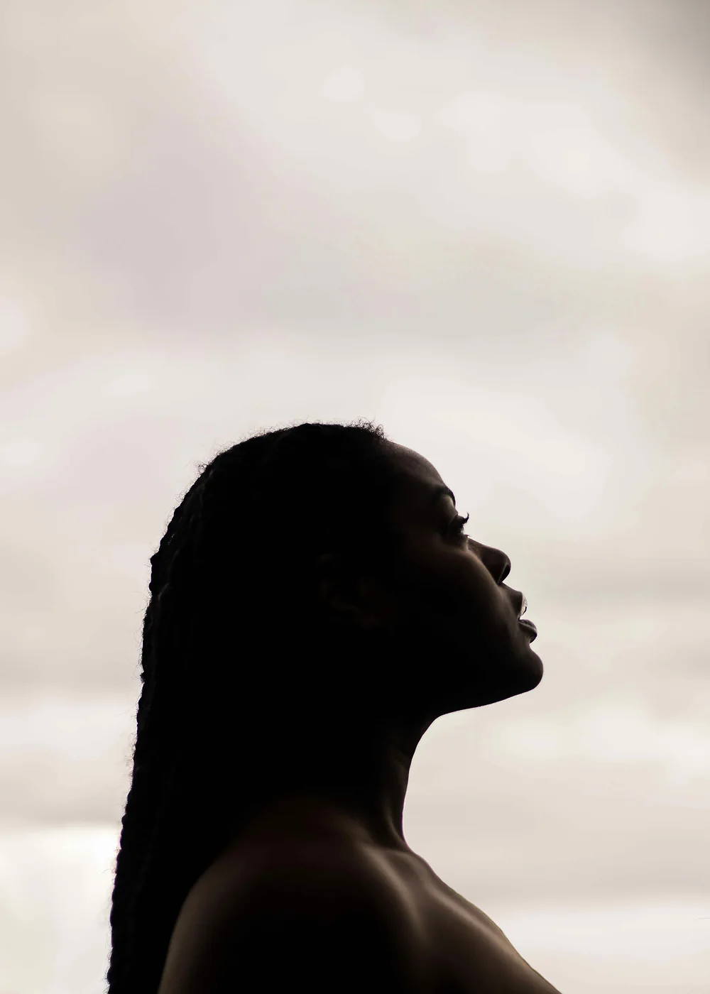 A woman in silhouette with her face tilted toward the sky